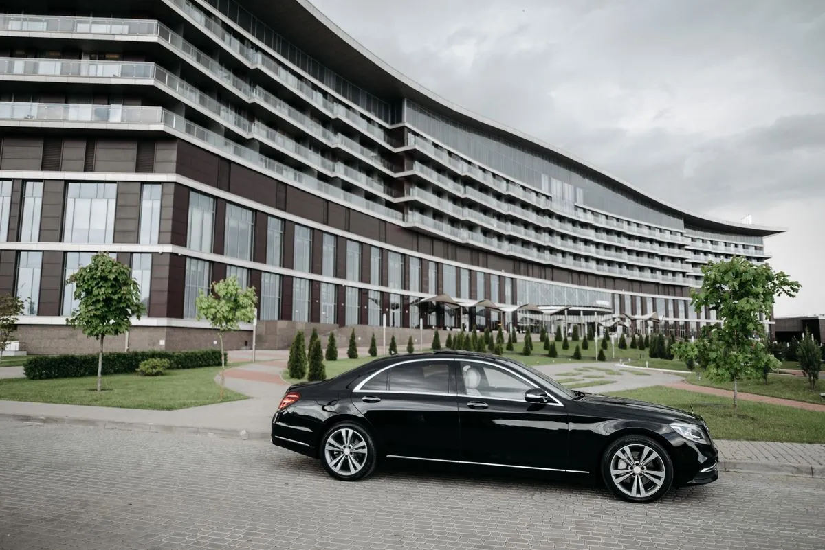 A black executive saloon waiting at the airport terminal kerb